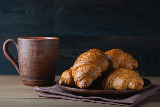 Cup of coffee and fresh croissants on wooden table