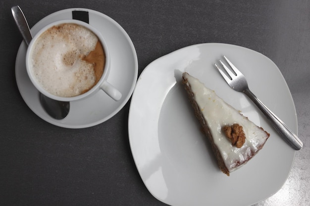 Cup of coffee and frosted carrot cake with chestnut view from top. Delicious cappuccino with pie