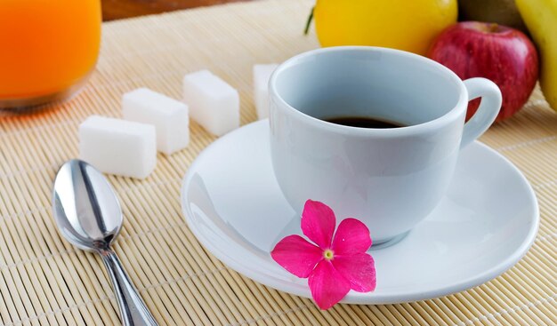 Cup of coffee and fruits on a bamboo place mat