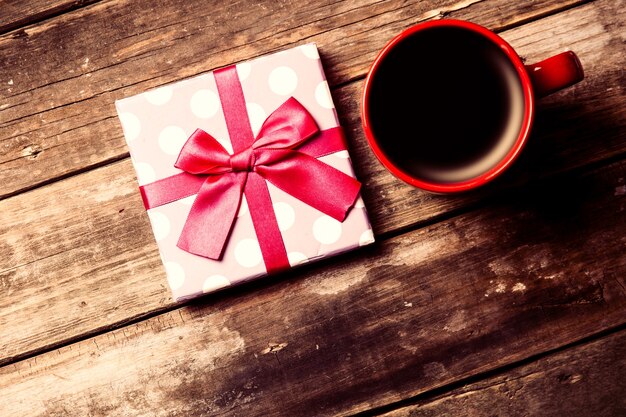 Cup of coffee and gift  on the brown wooden