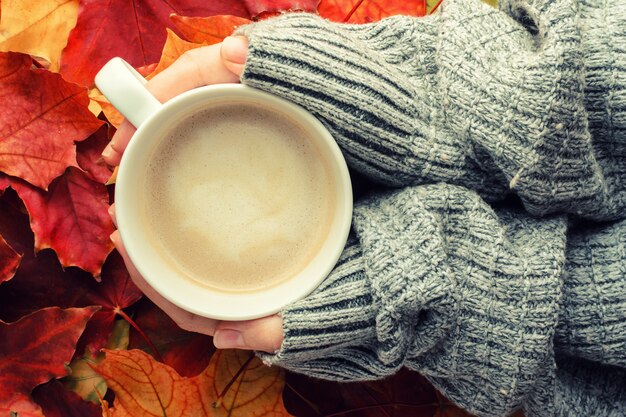 背景に対して木製のスツールに手でコーヒー1杯