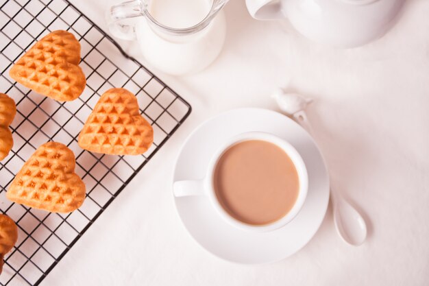 Cup of coffee and a heart shaped cookies on the baking rack