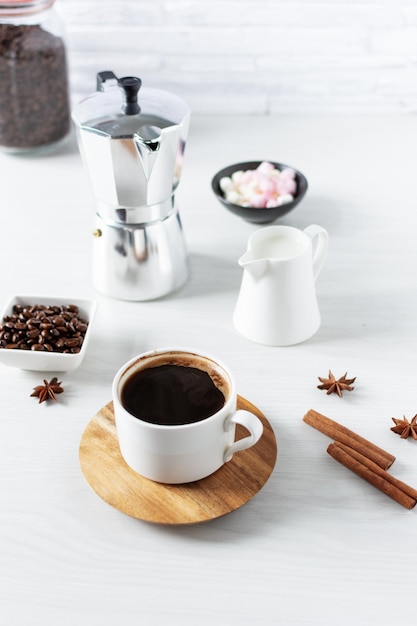 A cup of coffee and ingredients and equipment for making coffee on kitchen table