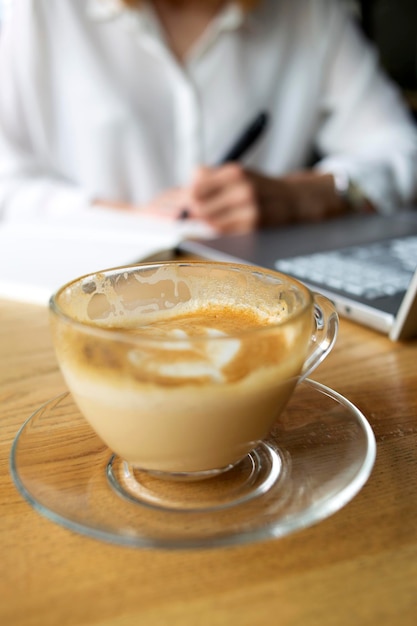 A cup of coffee, laptop and a girl behind