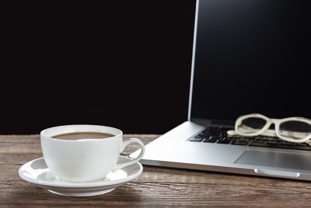 Photo cup of coffee and laptop on wooden table