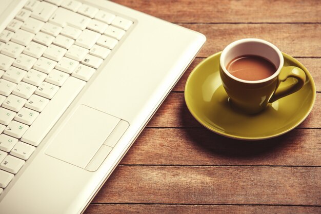 Cup of coffee and laptop on a wooden table