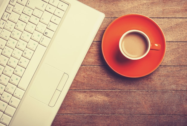 Cup of coffee and laptop on wooden table