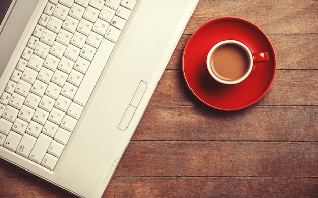 Cup of coffee and laptop on wooden table