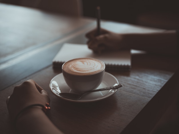 Arte del latte della tazza di caffè sulla caffetteria di legno della caffetteria dello scrittorio