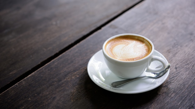 cup of coffee latte art on wood table.