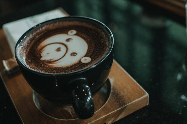 Photo cup of coffee latte and bear face bubble aet on wood table