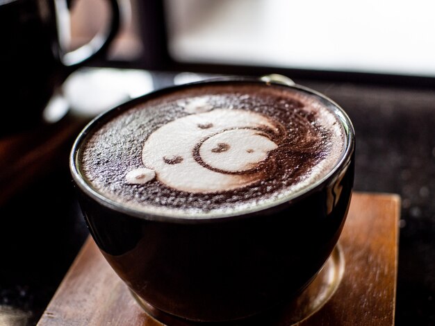 Cup of coffee latte and bear face bubble on wood table