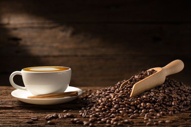 Cup of coffee latte and coffee beans on old wooden background