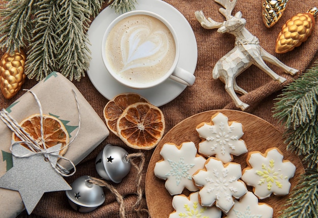 A cup of coffee latte homemade cookies and Christmas balls and knitted sweater