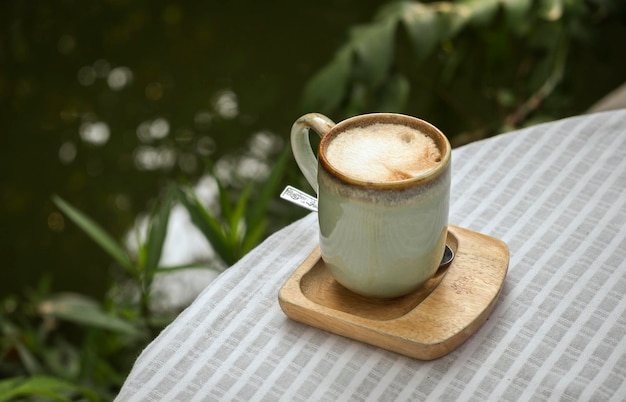 Cup of coffee latte with heart shape on old wooden background in the morning sunlight