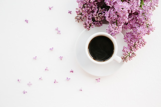 Photo cup of coffee and lilac branch on white