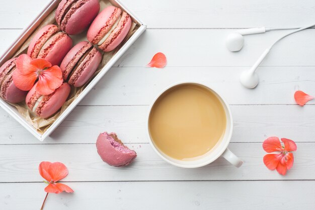 Cup of coffee, macaroon cookies in a box, flowers  with flat lay