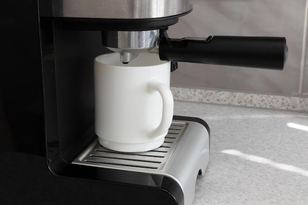 A cup in a coffee machine homemade coffee machine in the kitchen closeup