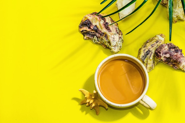 A cup of coffee in a marine style Starfish oysters palm leaves Hard light dark shadow bright yellow background flat lay top view