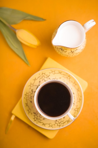 Cup of coffee and milk jug on the background