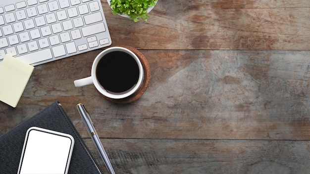 A cup of coffee mobile phone and notebook on wooden desk