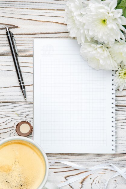 Cup of coffee and note pad on light wooden table