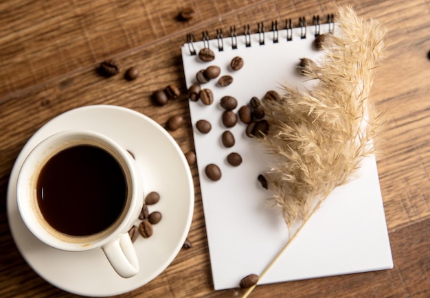 Cup of coffee notebook and coffee beans