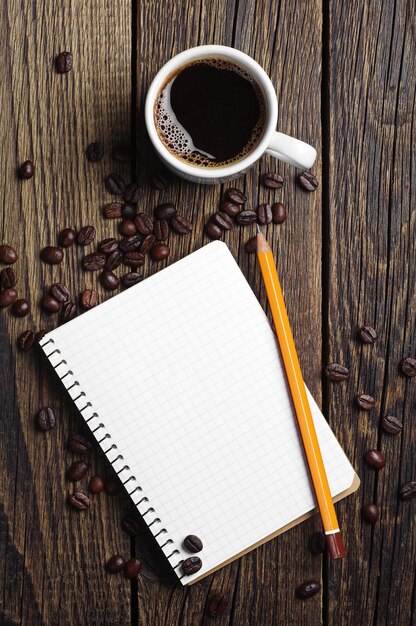 Cup of coffee and notepad on wooden background