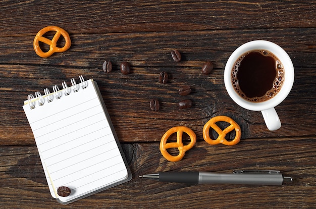 Cup of coffee and a notepad on the wooden table