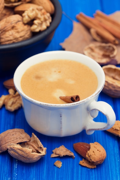 A cup of coffee and nuts on wooden surface