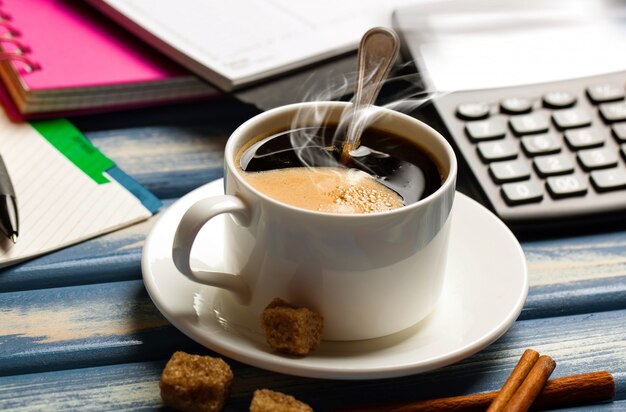 A cup of coffee in the office with items for doing business.