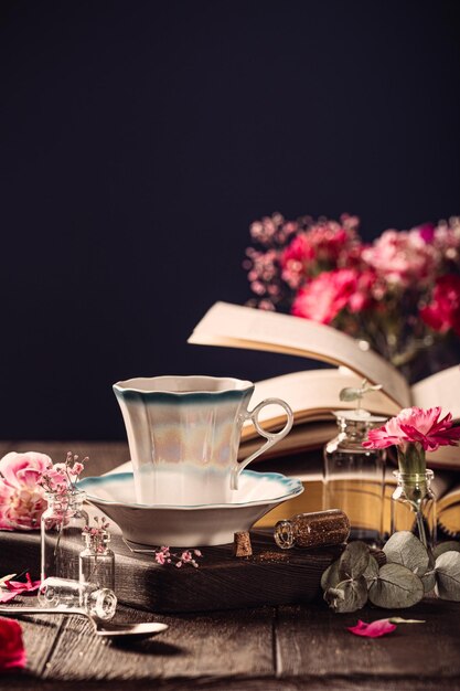 Cup of coffee old books and pink carnation flowers