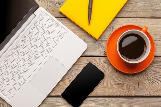 A cup of coffee on the orange plate on the wooden table. Office interior