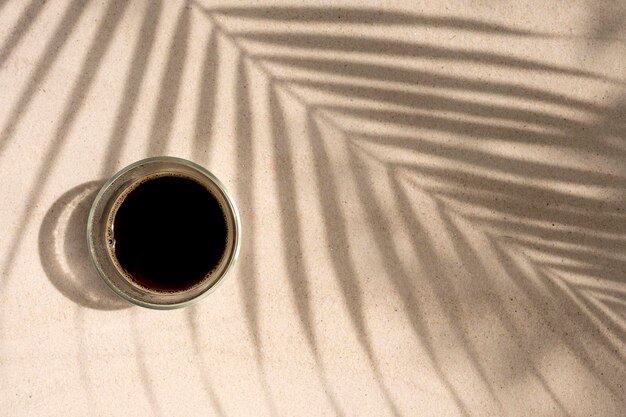 Cup coffee on palm shade at the beach