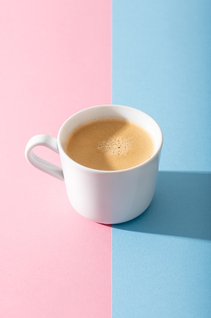 A cup of coffee on a pastel pink and blue background