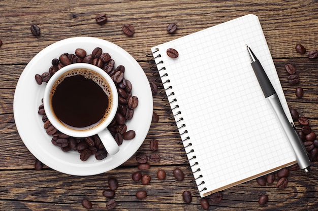 Cup of coffee, pen and opened notepad on desk