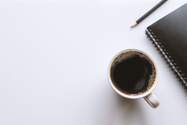 Cup of coffee, pencil and black notebook