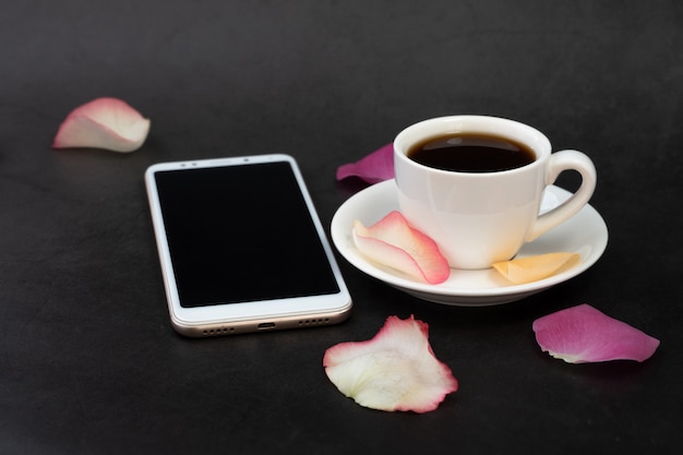 一杯のコーヒー、電話、バラの花びら。