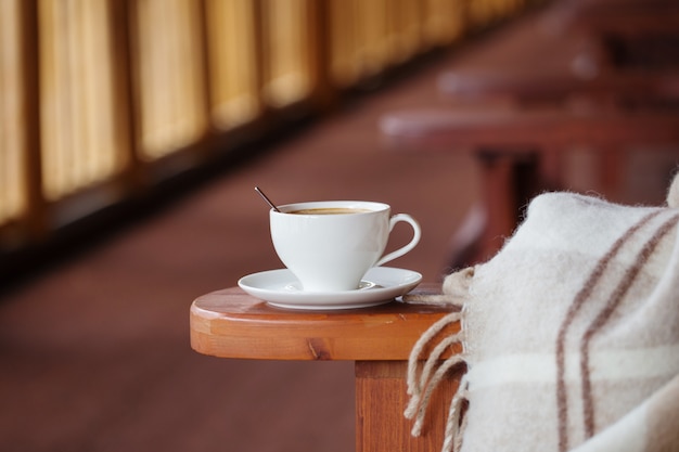 Cup of coffee and plaid on terrace