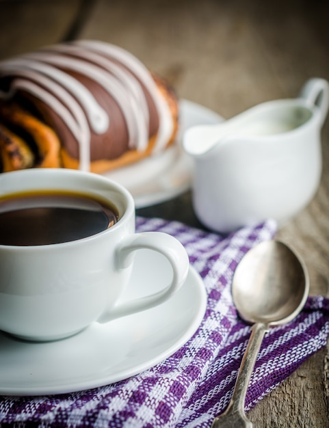 Cup of coffee and poppy bun glazed with ganache