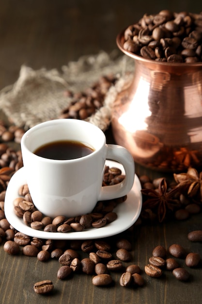 Cup of coffee and pot on wooden background