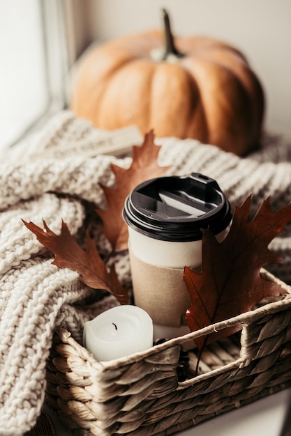 Cup of coffee, pumpkin, dried autumn leaves on window. Autumn composition.