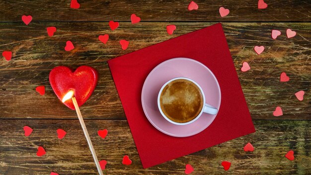 Foto una tazza di caffè su un tovagliolo rosso e accendere una candela a forma di cuore con una lunga partita un giorno romantico