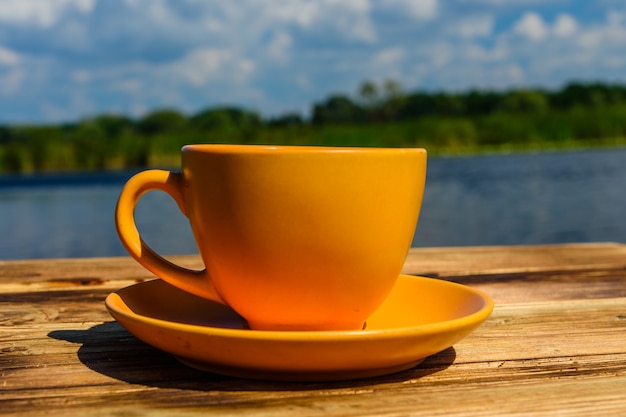 Cup of coffee on rustic wooden table at the riverside