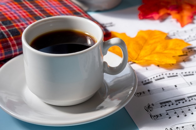 Foto tazza di caffè su un piattino su sfondo blu. note musicali e una tazza di caffè