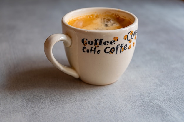 Cup of coffee on a saucer on a gray table