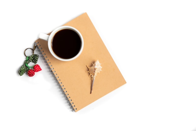 Cup of coffee and a seashell on a notebook