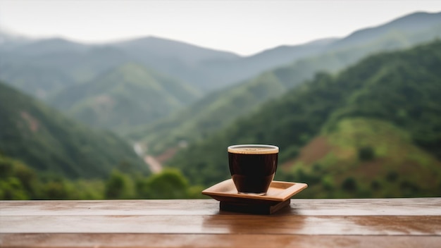 A cup of coffee sits on a table in front of a mountain landscape.