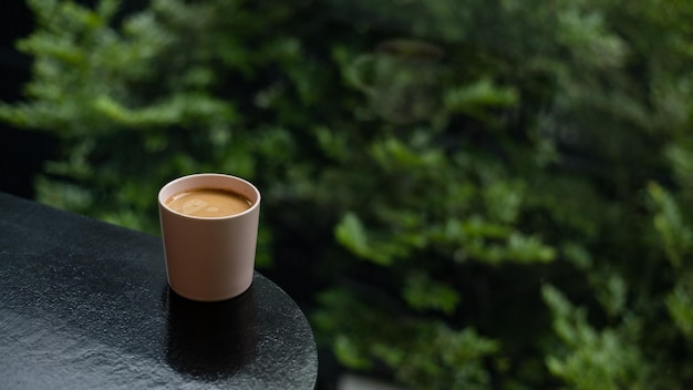 A cup of coffee sits on a table with a green background.