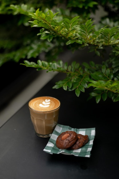 A cup of coffee and a small plate of chocolate chip cookies sit on a table